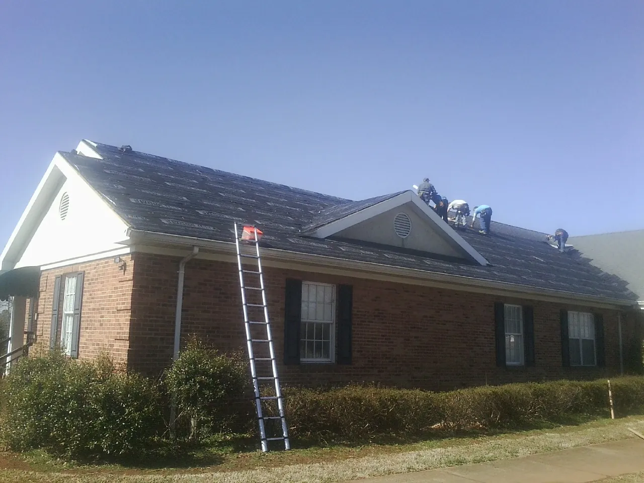 Crew tearing shingles off a brick ranch roof with a ladder set — Metal Roof Repair work by our crew in Moraga
