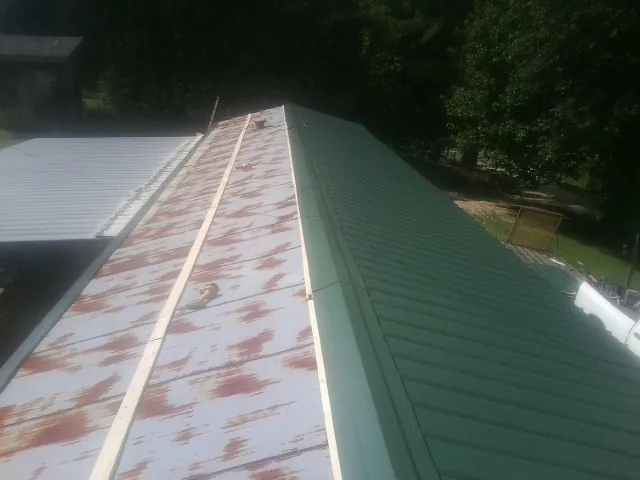 Old rusted panels beside newly installed green metal roofing — Wind Damage Roof Repair by Roofing Brothers in Moraga