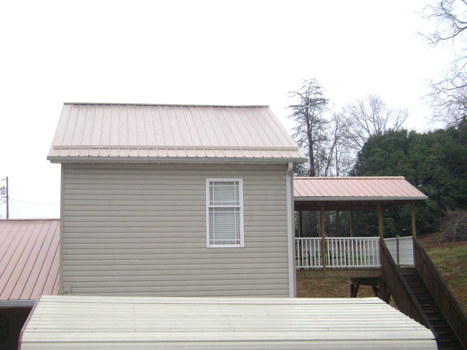 Tan metal roofs on a two story addition and attached porch, from a Roof Replacement job in Moraga